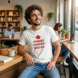 Man wearing a white t-shirt with red " Insert Cheesy Bread" text sitting in a cafe.