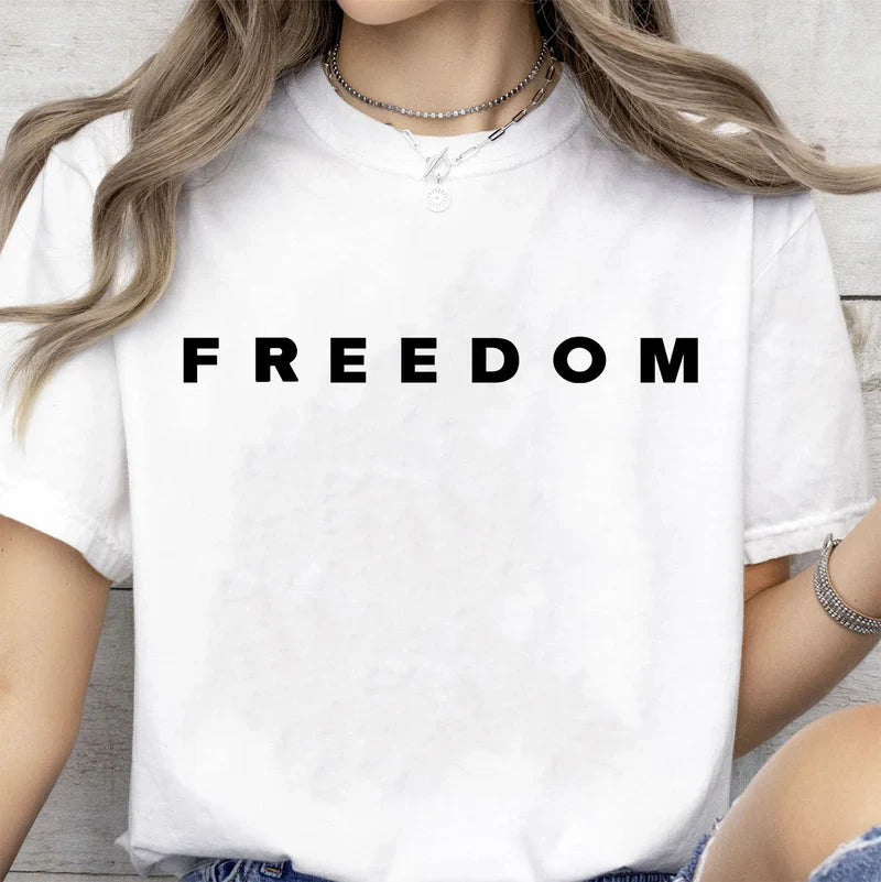 Person wearing a white t-shirt with 'FREEDOM' printed on it.
